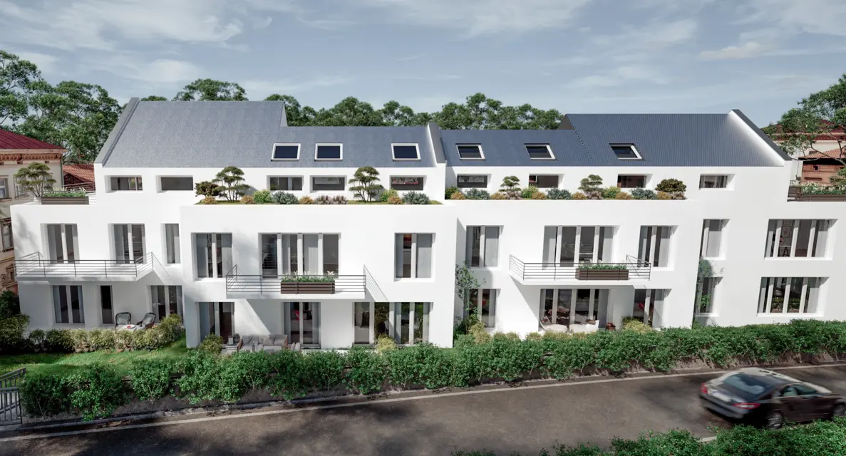 Modernes weißes Apartmentgebäude mit Balkonen und Dachgärten, gelegen in einer von Bäumen gesäumten Wohnstraße mit parkenden Autos unter einem teilweise bewölkten Himmel.